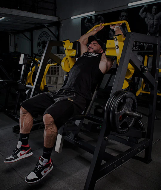 Hombre entrenando el pecho en una máquina de press inclinado en un gimnasio